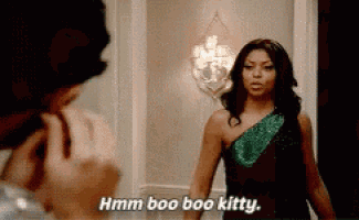 a woman in a black dress is talking to a man in a room and says hmm boo boo kitty .