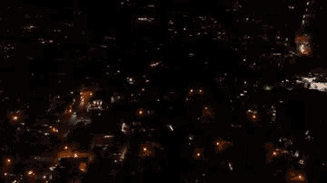 an aerial view of a city at night with lots of lights on buildings .