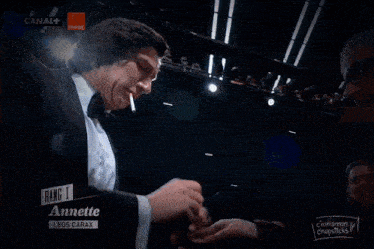 a man in a tuxedo is smoking a cigarette in front of a canal + sign