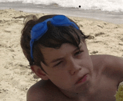 a young boy wearing swimming goggles on a beach