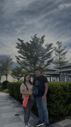 a man and a woman are posing for a picture in front of trees