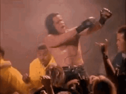a man without a shirt is dancing in front of a crowd of people .