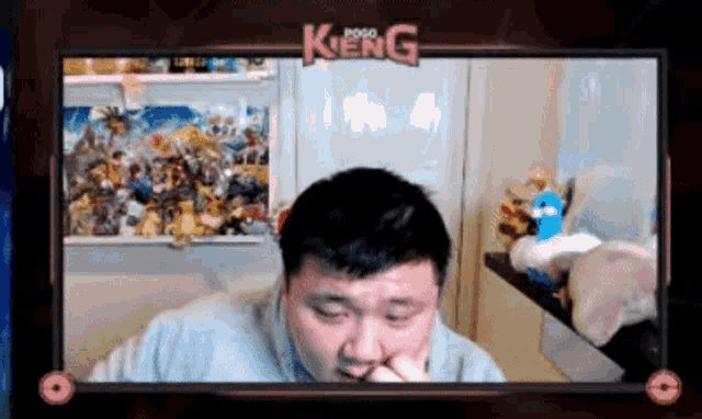 a man is sitting in front of a computer screen with his hands on his face .