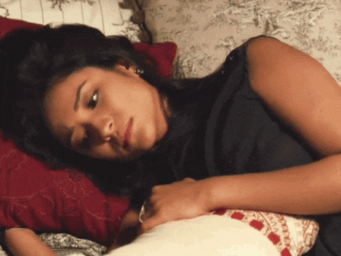 a woman laying on a bed with a pillow that says ' a ' on it