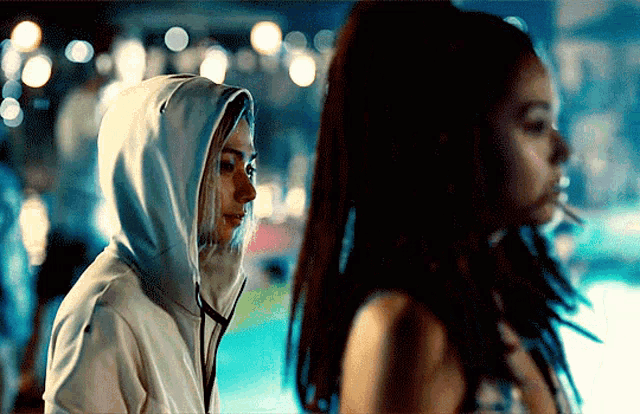 a woman in a white hoodie is standing next to another woman