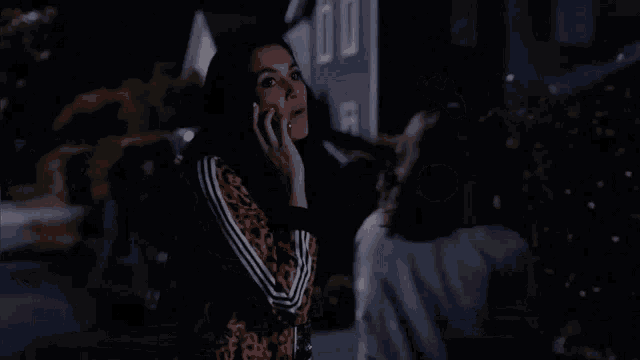 a woman is talking on a cell phone while a man looks on .