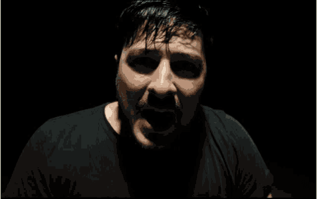 a man with a beard is making a funny face in a dark room