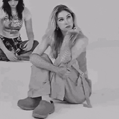 a black and white photo of a woman sitting on the floor with her legs crossed .