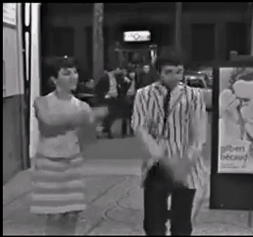 a man and a woman are dancing in front of a sign that says albert becay