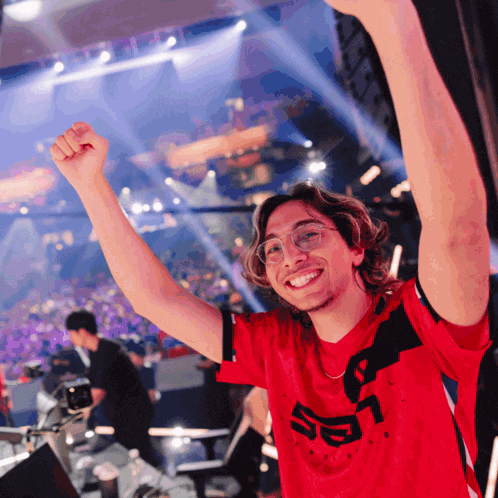 a man wearing a red shirt with the letter s on it holds his fist in the air