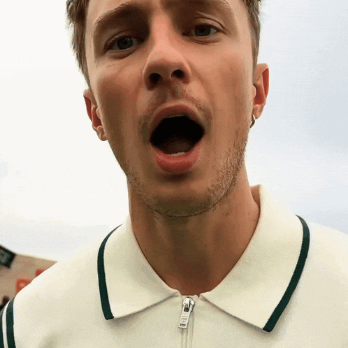 a close up of a man 's face with his mouth open and a zipper on his shirt that says ' abercrombie '