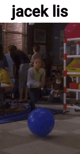 a child is playing with a blue ball in a classroom with the words jacek lis on the top