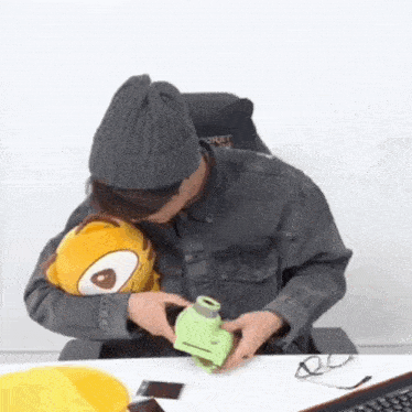 a man is sitting at a table with a stuffed animal and a camera .