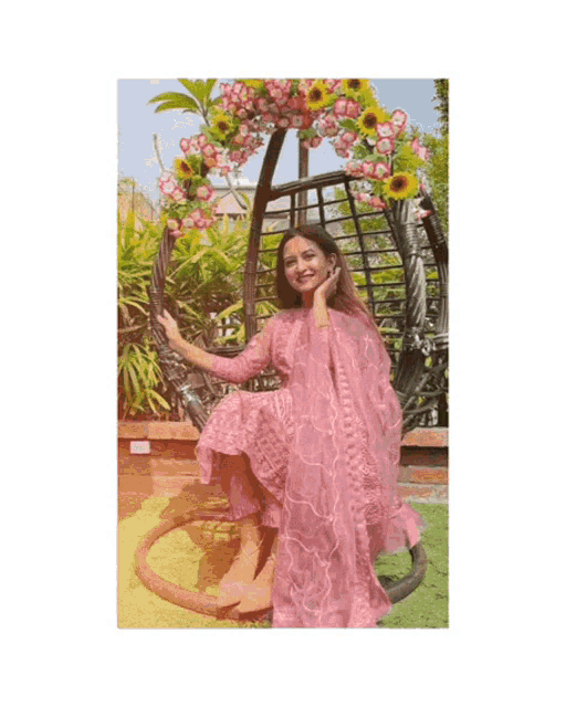 a woman in a pink dress is sitting in a chair with flowers in the background