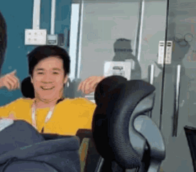 a man in a yellow shirt is sitting in a chair in an office .