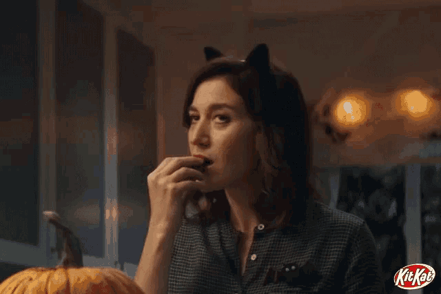 a woman wearing cat ears eating a kit kat