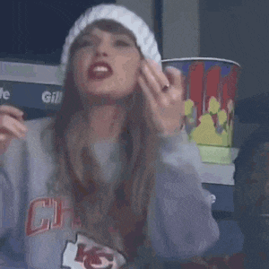 a woman wearing a kansas city chiefs sweatshirt and a white hat is making a funny face .