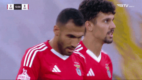 two soccer players are standing next to each other during a game and the score is 2 to 0