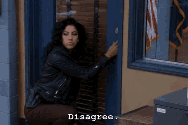 a woman in a leather jacket is kneeling down in front of a blue door with the words disagree written on the bottom
