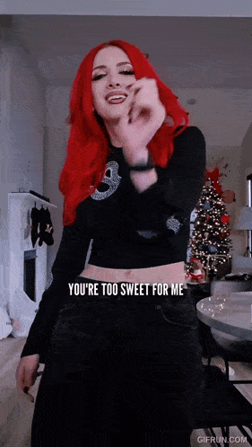 a woman with red hair is standing in front of a christmas tree and says " you 're too sweet for me "