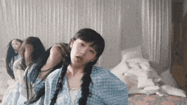 a woman in a blue plaid shirt is sitting on a bed with other women