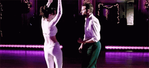 a man and a woman are dancing on a dance floor in a room .