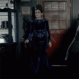 a woman in a blue velvet dress is standing in front of a door .