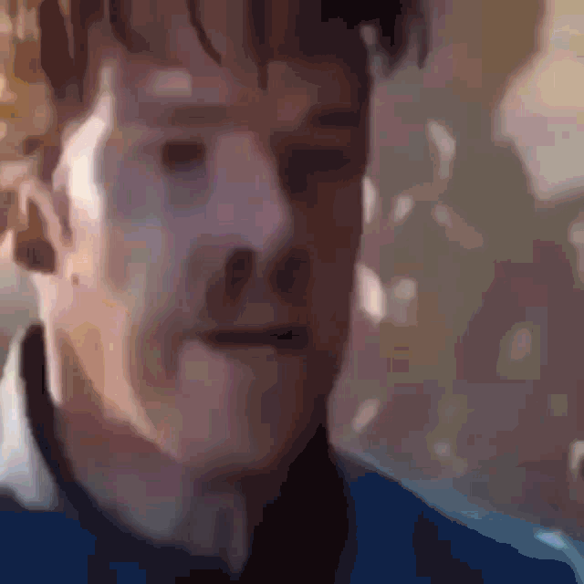 a close up of a man 's face with a blue shirt and tie