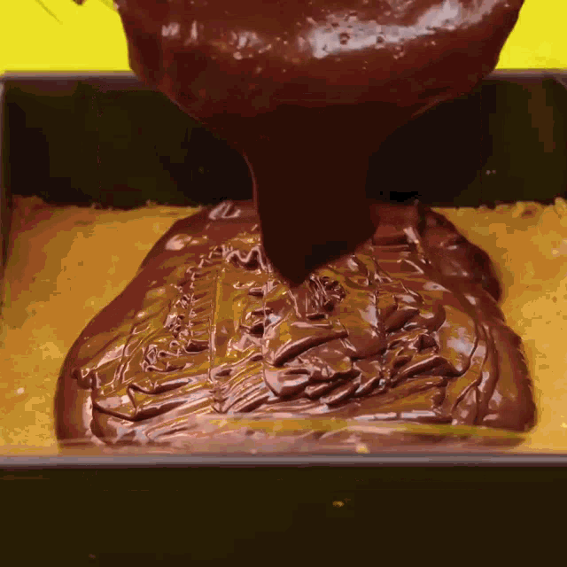chocolate is being poured on a cake in a square pan
