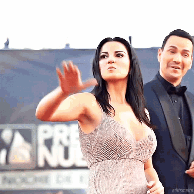 a woman in a dress is standing next to a man in a tuxedo in front of a sign that says premios