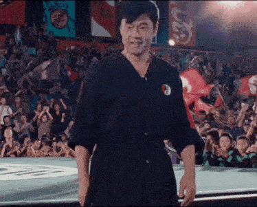 a man in a karate uniform stands in front of a crowd of people