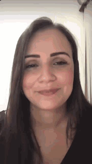 a woman with long hair is smiling and looking at the camera .