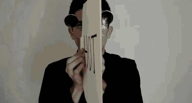 a person is holding a piece of paper with the word hot written on it in front of their face .