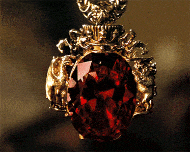 a close up of a pendant with a large red stone in the center