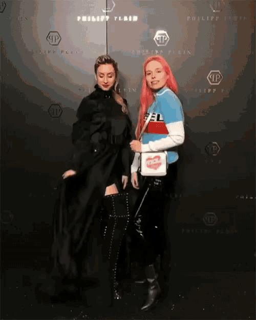 two women standing in front of a wall that says philipp plein on it