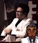 a man in a white suit is sitting in a chair next to a cartoon of a man in a suit .