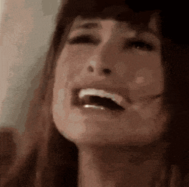a close up of a woman 's face with her mouth open and her teeth showing .