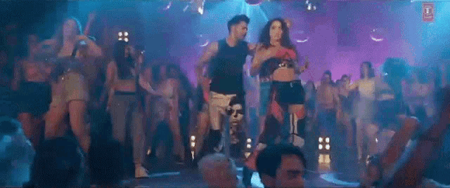 a group of people are dancing in a club in front of a crowd of people .
