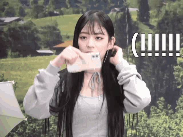 a girl taking a picture of herself with a phone with a landscape in the background