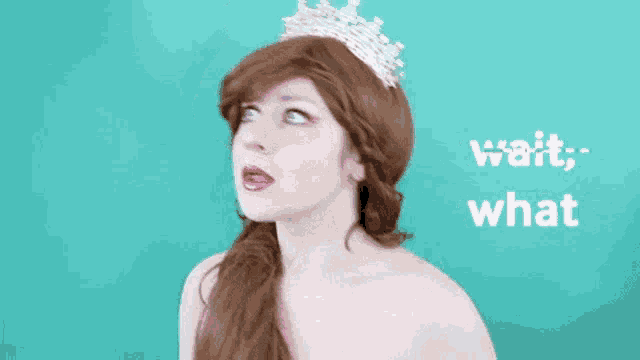 a woman wearing a tiara and a wig says " wait what "