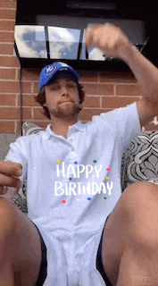 a man wearing a happy birthday shirt is sitting on a couch