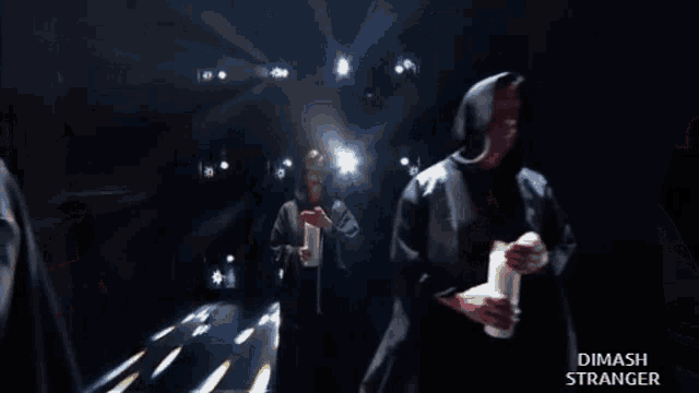 a man in a hooded jacket is standing in a dark room with the words dimash stranger below him