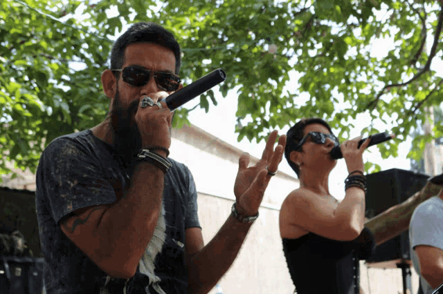 a man and a woman singing into microphones outdoors