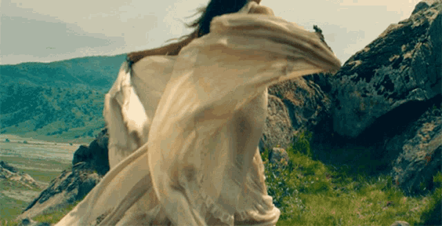 a woman in a long white dress is standing in a grassy field