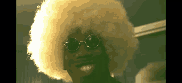 a man wearing sunglasses and an afro wig is smiling