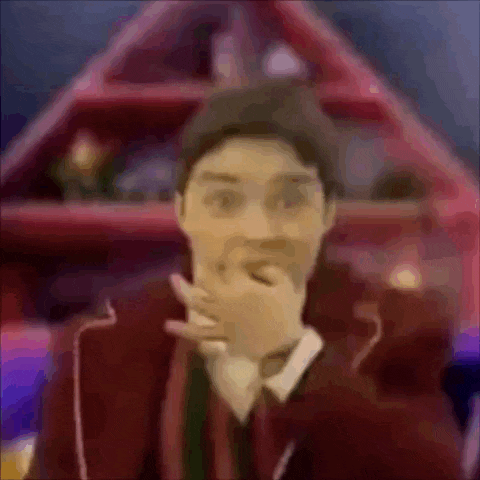 a blurry picture of a man in a suit covering his mouth with his hand .