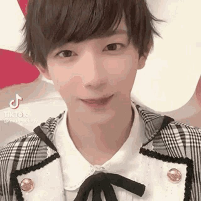 a young man wearing a plaid jacket and a white shirt with a bow tie .
