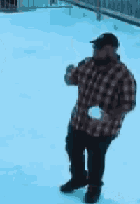 a man in a plaid shirt is standing in the snow holding a ball .