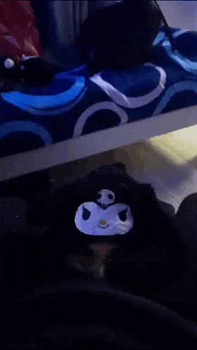 a black stuffed animal with a white face is sitting on a bed .