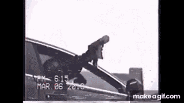 a person is standing in a car with a gun in the window .